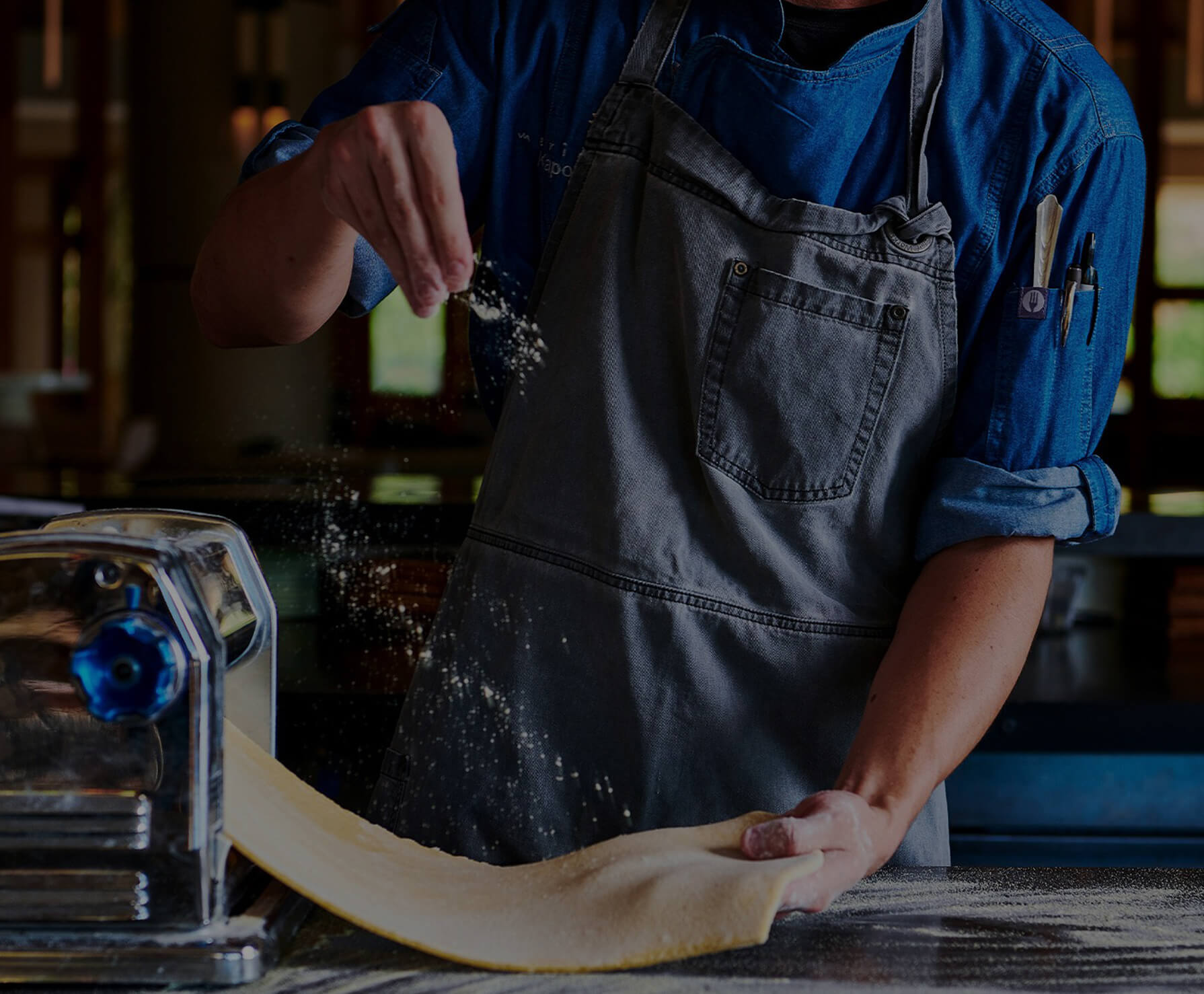 A chef sprinkling flour on pasta